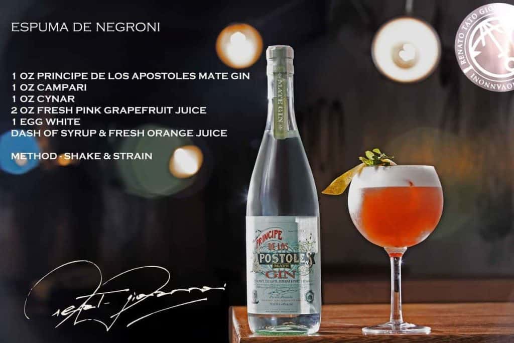 Neben einem mit einer Orangenspirale garnierten Cocktail steht eine Flasche „Principe de los Apostoles“ Mate-Gin; das Cocktailrezept und die Zubereitungsanleitung sind auf der linken Seite aufgeführt, in den Ecken befinden sich eine Unterschrift und ein Siegel.