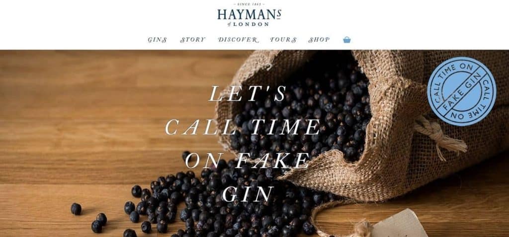 Ein Jutesack, aus dem dunkle Beeren auf eine Holzfläche rieseln, darüber der Text „LETS CALL TIME ON FAKE GIN“. Oben sind das Logo von Haymans of London und das Navigationsmenü zu sehen.