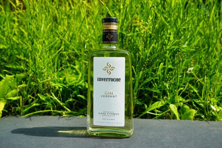 Eine Flasche Inverroche Gin Verdant steht auf einer Schieferfläche vor dem Hintergrund von üppigem grünem Gras und fängt damit perfekt die Essenz der frischen Botanicals und den lebendigen Charakter des Inverroche Gin Verdant ein.