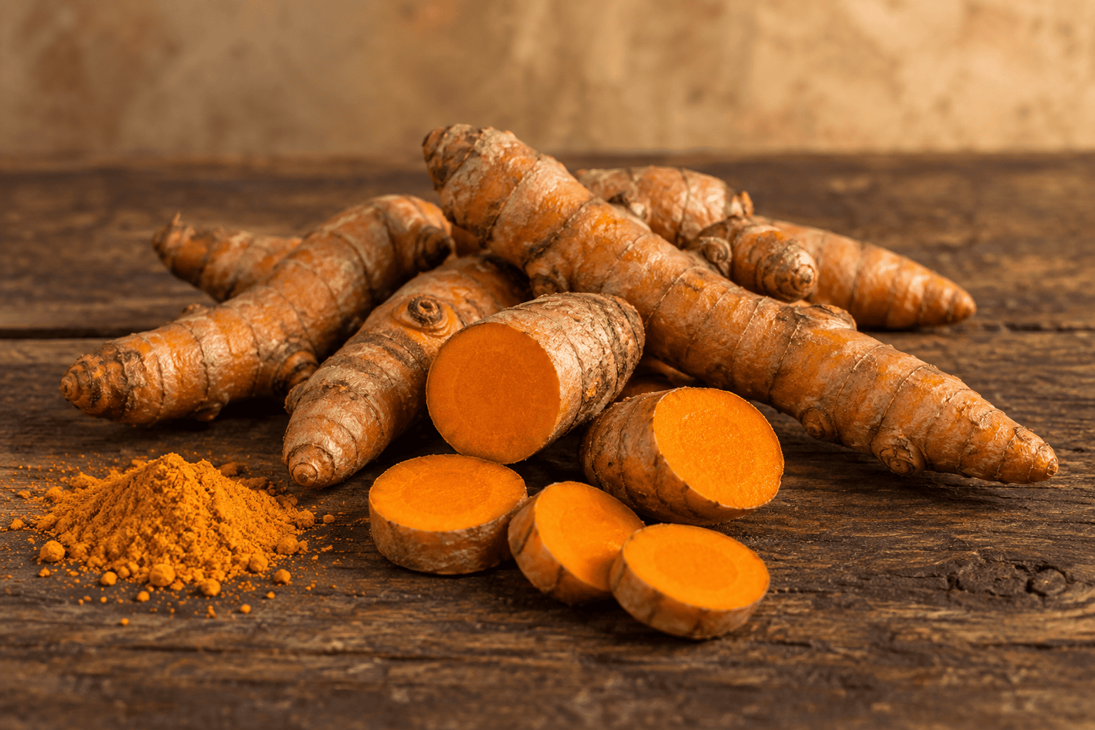 Kurkumawurzeln, aufgeschnitten mit orangem Inneren, und Kurkumapulver